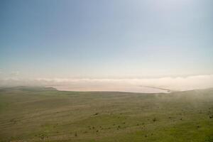 A foggy day with a large body of water in the background. The sky is clear and blue. photo