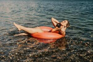 A woman is floating on a red inflatable raft in the ocean photo