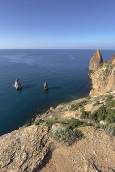 A rocky cliff overlooks the ocean with a blue sky in the background photo