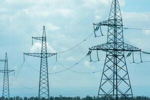 High voltage towers with sky background. Power line support with wires for electricity transmission. High voltage grid tower with wire cable at distribution station. Energy industry, energy saving photo