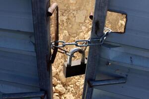 An old metal lock hangs on the fence. photo