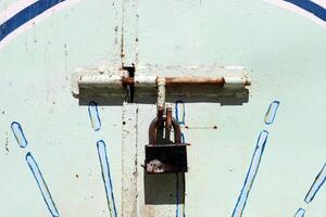 An old metal lock hangs on the fence. photo