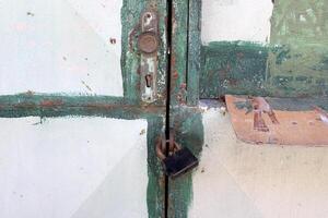 An old metal lock hangs on the fence. photo