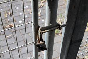 An old metal lock hangs on the fence. photo