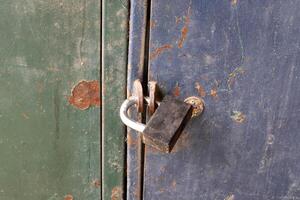 An old metal lock hangs on the fence. photo