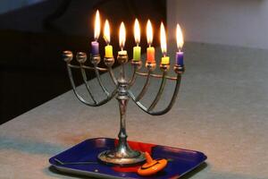 A burning wax candle stands on the table. photo