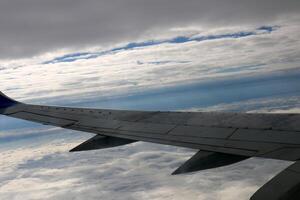The wing of a jet plane and the scenery on the ground are visible through the porthole. photo