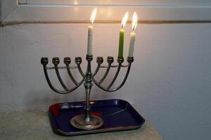 A burning wax candle stands on the table. photo