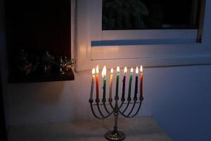 A burning wax candle stands on the table. photo