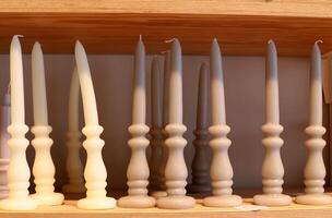 A burning wax candle stands on the table. photo