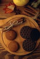 Cookies with pumpkins and apples on the table. Chocolate chip cookies with apples and pumpkins in the background lie on a wooden table. photo