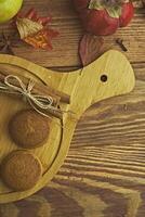 Cookies with pumpkins and apples on the table. Chocolate cookies with apples and pumpkins are on a wooden table. photo