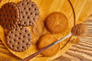 A pile of cookies and a spoonful of cocoa. Top view photo