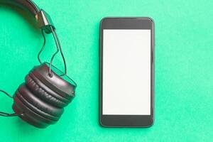 Headphones and smartphone on colorful background. Flat lay concept. headphones and telephone on green pastel backgrounds. photo