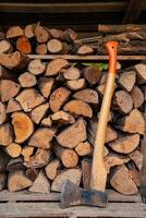 Axe in front of a stack of wood in a woodshed. Natural vertical background. photo