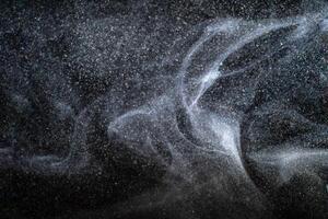 Dust particles cloud generating abstract shapes with black background and copy space for text. photo
