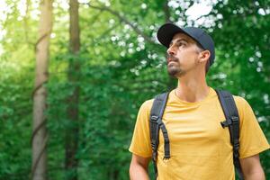 Young Man With Backpack hiking in a forest. Discovery Travel Destination Concept photo