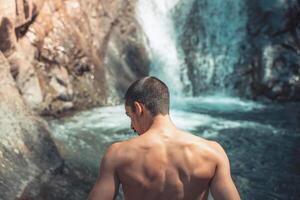 Summer background back shot of a male in front of crystal clear waterfalls. photo