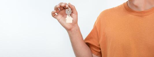 Banner of young man with the new home keys. Keychain in the shape of a wooden house. photo