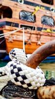 Mooring Knot, Close-Up, from Which Ropes Extend to Stern of Ship Holding it in Bay, Concept of Reliability photo