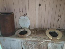 Abandoned Outhouse with Two Old Toilet Seats photo