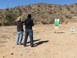 Anonymous Men Practicing Target Shooting in the Desert photo