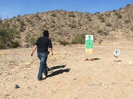 Anonymous Man Practicing Target Shooting in the Desert photo