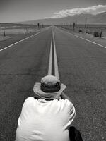 Man Taking Picture in Middle of Deserted California Highway photo