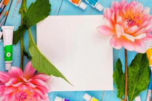 summer background. dahlias and a canvas on a blue wooden background. art. space for a text photo