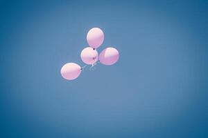 Light pink balloons in blue summer sunny sky flying up and away photo