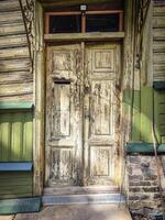 Old building wooden door with textured surface, a hole for mail and a round handle photo