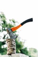 Axe with orange handle sticks out in hemp against photo