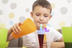 Child making ice cream from fruit juice on table at home photo