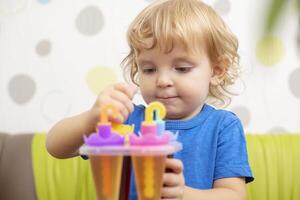 Child making ice cream from fruit juice on table at home photo
