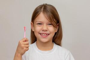 Portrait of caucasian happy little girl with open wide smile showing tooth brush and teeth looking at camera on white background photo