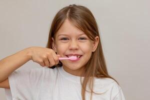 Portrait of caucasian happy little girl with open wide smile holding tooth brush near teeth looking at camera on white background photo