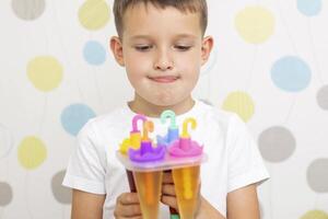 Child making ice cream from fruit juice on table at home photo