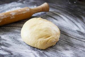 Fresh dough ready to bake. Bread dough on wooden kitchen counter with rollingpin photo