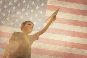 Little boy launches a paper plane into the air on the flag of america background photo