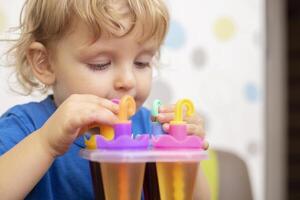 Child making ice cream from fruit juice on table at home photo