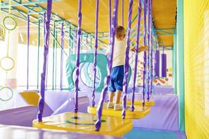 Child navigating through purple and yellow play structure in indoor playground. photo