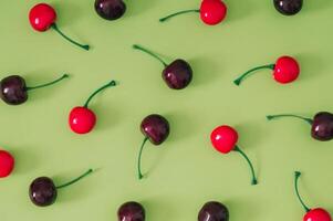 Trendy fruit pattern made of red cherries on pastel green background. Minimal food layout. Nature summer fruit concept. Cherry fruit aesthetic. Flat lay, top of view. photo