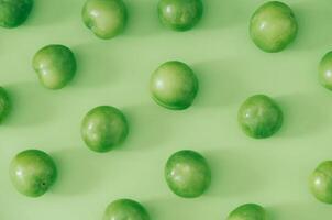 Trendy fruit pattern made of fresh green plums on light pastel green background. Minimal layout. Nature summer concept. photo