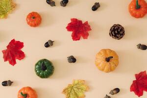 Creative autumn or fall pattern made with colorful fallen leaves, pumpkins, pinecone and nuts on beige background. Minimal retro vintage autumn concept. Season nature flat lay. Autumn aesthetic. photo