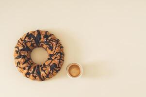 Delicious cake with chocolate topping and cup of coffee on pastel cream background with copy space. Minimal sweet dessert concept. Creative yummy cake with espresso idea. Cake aesthetic. Flat lay. photo