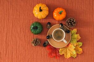 Colorful autumn or fall scene made with autumn leaves, nuts and cup of coffee on brown muslin background. Minimal seasonal concept. Nature flat lay composition. photo