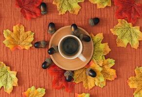 Colorful autumn or fall pattern made with autumn leaves, nuts and cup of coffee on brown muslin background. Minimal seasonal concept. Nature flat lay composition. photo