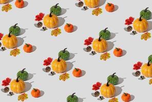 Trendy autumn or fall pattern made with pumpkins, yellow and red fallen leaves, nuts and pinecones on white background. Minimal autumn objects composition. Nature flat lay. Season concept. photo