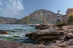 Man Tourists Standing on Cliff near Lighthouse in Montenegro photo