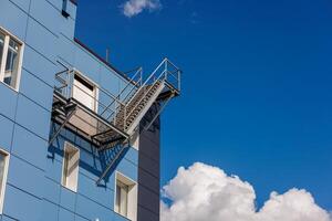 Azure building with a side fire escape, under a sky with fluffy clouds photo